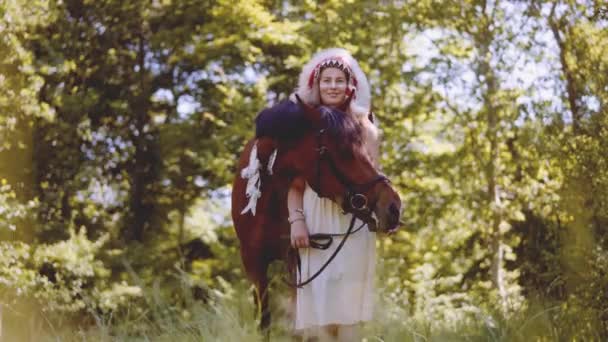 Женщина в головном уборе с лошадью в лесу — стоковое видео