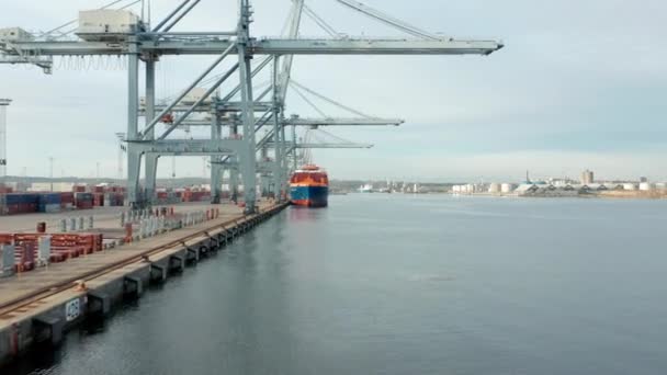Schip aangemeerd in de haven van een containerscheepswerf met uitzicht op de Skies — Stockvideo