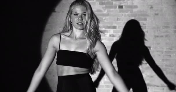 Una bailarina vibrante interactúa con la cámara mientras balancea su cuerpo sobre un fondo oscuro — Vídeo de stock