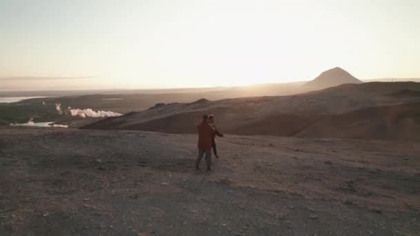 Due turisti che scattano foto in un vasto campo roccioso ricoperto di sporcizia marrone e sabbia — Video Stock