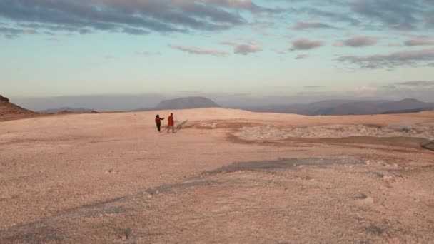 Dois turistas caminhando no vasto campo geotérmico no fundo — Vídeo de Stock