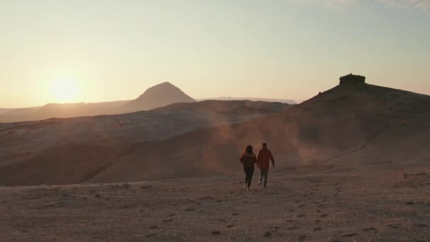 Luftaufnahme eines Paares, das auf einen Berg zuläuft, und Sonnenuntergang im Hintergrund — Stockvideo