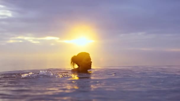 Belle femme détendue et plongée dans la piscine à débordement pendant le coucher du soleil doré — Video