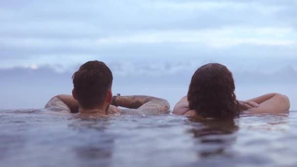 Par doppade i en het oändlighetspool med den ljusa himlen i bakgrunden — Stockvideo