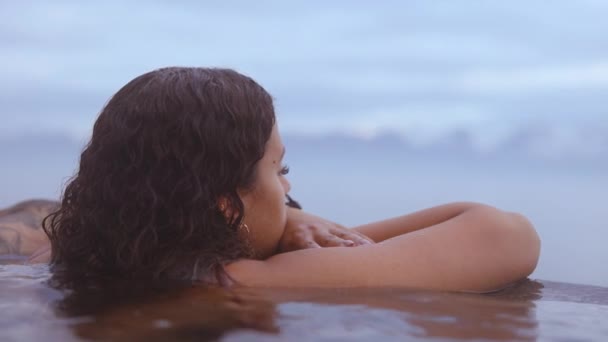 Mulher bonita mergulhada em uma piscina infinita com a vista desfocada — Vídeo de Stock