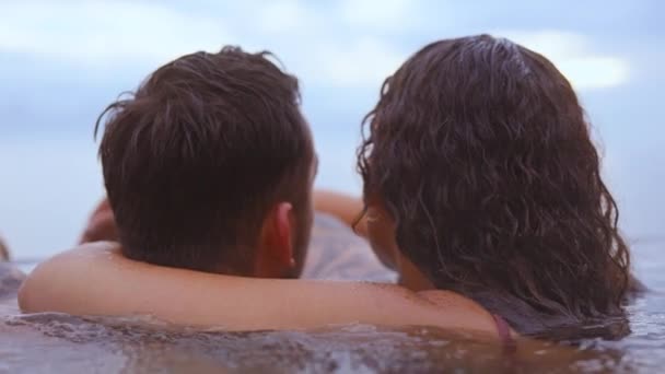 Tiro íntimo de una pareja acurrucándose mientras se baña en una piscina infinita — Vídeo de stock