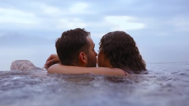 Пара будучи интимной во время купания в бассейне бесконечности с видом на голубые небеса — стоковое видео