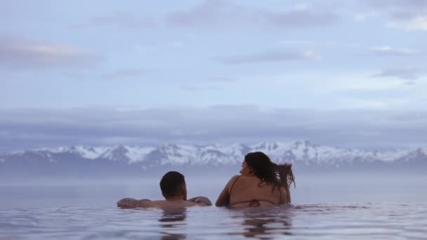 Casal por uma piscina infinita, montanhas majestosas com montanhas cobertas de neve — Vídeo de Stock