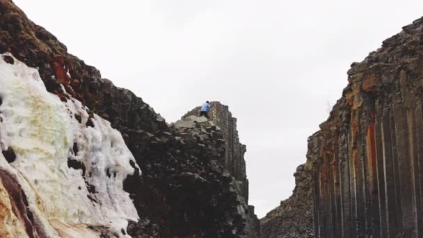 Uomo in piedi sulla cima delle colonne di roccia di basalto sotto il cielo limpido — Video Stock