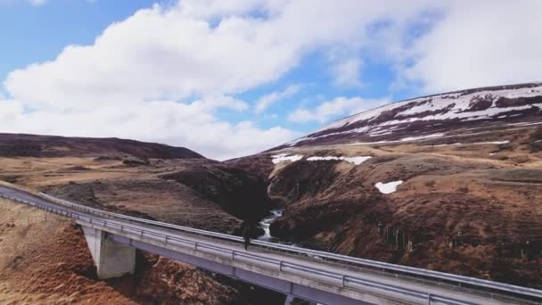 Montaña y hombre Paseando en el estrecho puente bajo las aguas que fluyen — Vídeo de stock