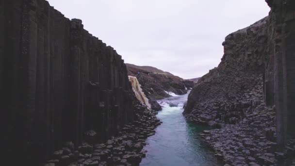 Coluna de rocha de basalto com o deslumbrante rio glaciar azul sob os céus claros — Vídeo de Stock