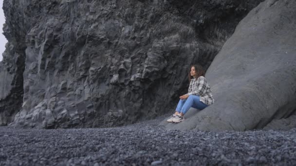 Vista da paisagem de uma fêmea sentada no lado das colunas de basalto de Gardar — Vídeo de Stock