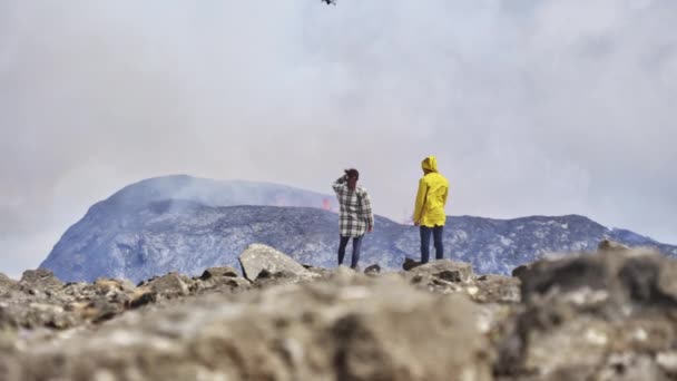 Nyílt terepen a turisták élvezik a kilátást egy kitörő vulkán égbolt alatt — Stock videók