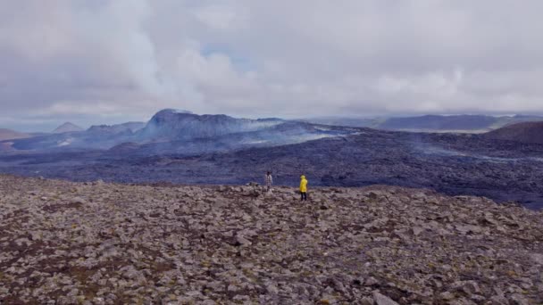 Мандрівники стоять на вершині скелястого поля, звідки видно гірські хребти з Афар. — стокове відео