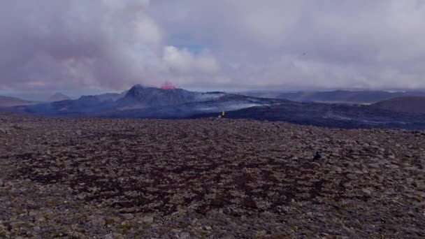 Vaste champ ouvert avec des aventuriers regardant un volcan en éruption avec un nuage moelleux — Video