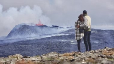 Aktif bir volkanın sahnesini izlerken bir çiftin kucaklaşmasının havadan çekimi