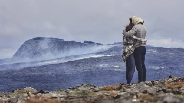 Captura aérea de paisaje de un volcán activo y vista de una dulce pareja acurrucada — Vídeos de Stock