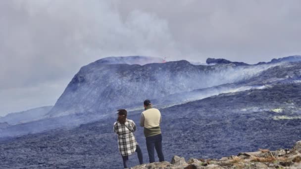Aventureros audaces observando un volcán en erupción y los majestuosos cielos nublados — Vídeo de stock