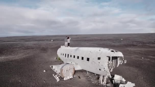 背景にある飛行機の難破船と曇った空の上での旅行者の空中ショット — ストック動画