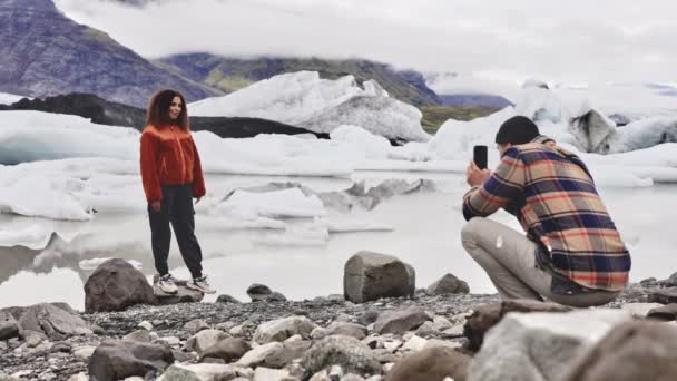 Снимок женщины-туриста, позирующей для фотографии с ледником на заднем плане — стоковое видео