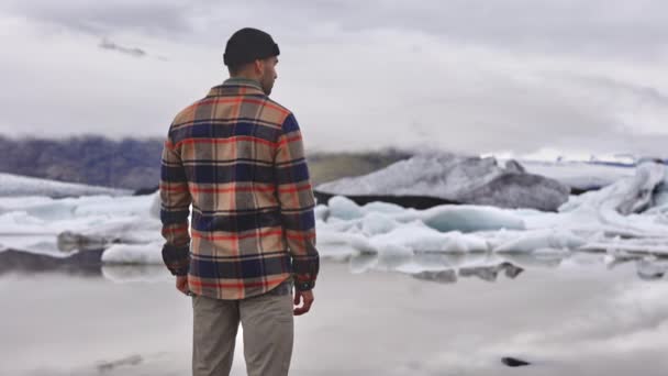 Muž v Plead Shirt obdivovat krásné ledovce tání u jezera na Islandu — Stock video