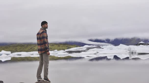 Turista em pé para admirar o lago e derreter geleira na Islândia — Vídeo de Stock