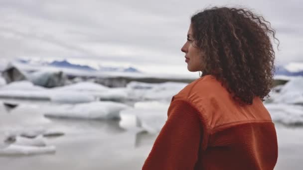 Utsikt över smältande glaciär i bakgrunden och porträtt skott av kvinna — Stockvideo