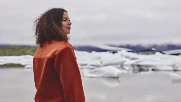Кудрявая туристка, стоящая посреди ледниковых полей Исландии — стоковое видео