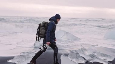 İzlanda 'da elmas plajı boyunca yürüyen fotoğrafçı.
