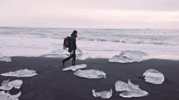 Фотограф, гуляющий по алмазному пляжу Исландии — стоковое видео