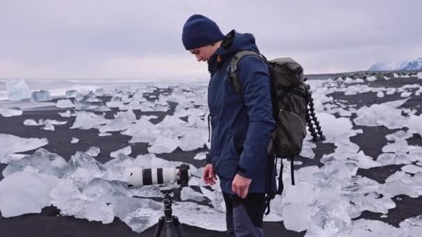 Фотограф на Даймонд-Бич возле ледниковой лагуны Исландии — стоковое видео