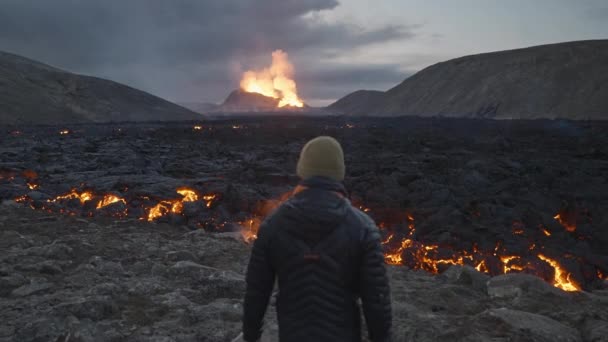 Hombre caminando hacia el flujo de lava desde el eruptivo volcán Fagradalsfjall — Vídeos de Stock