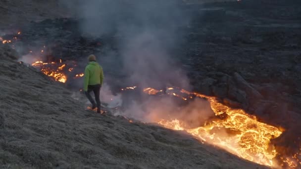 Homem caminhando ao lado do fluxo de lava de romper o vulcão Fagradalsfjall — Vídeo de Stock