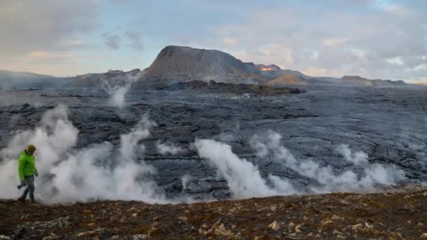 Fotógrafo caminando junto al flujo de lava desde el eruptivo volcán Fagradalsfjall — Vídeos de Stock