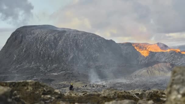 Человек, идущий по ландшафту, извергая вулкан Фаградальсфьолл в Исландии — стоковое видео