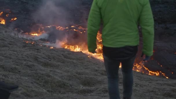 Hombre caminando hacia el flujo de lava desde el eruptivo volcán Fagradalsfjall — Vídeos de Stock