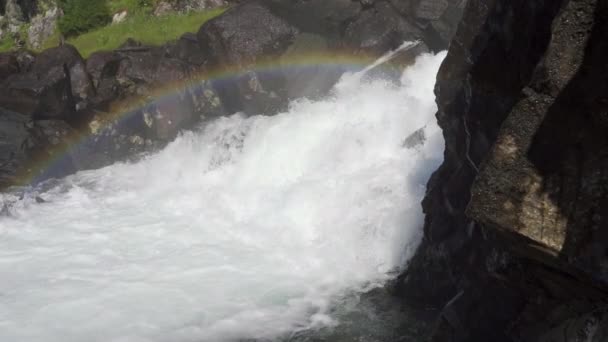 Água em cascata sobre rochas com névoa criando arco-íris acima — Vídeo de Stock