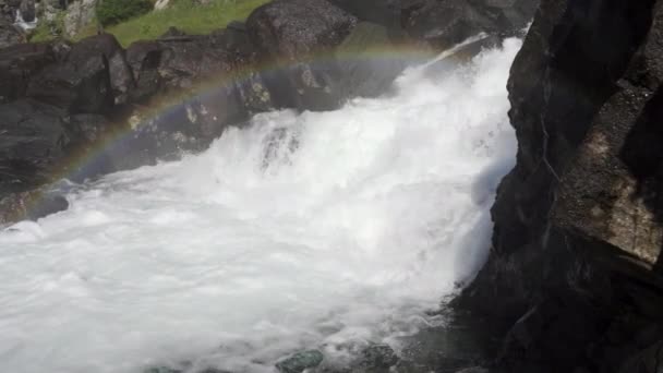 Água em cascata sobre rochas com névoa criando arco-íris acima — Vídeo de Stock