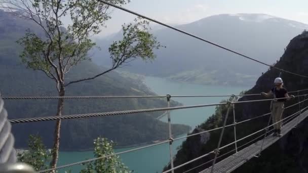 Escalador de rocas caminando a través del estrecho puente de cuerda — Vídeo de stock