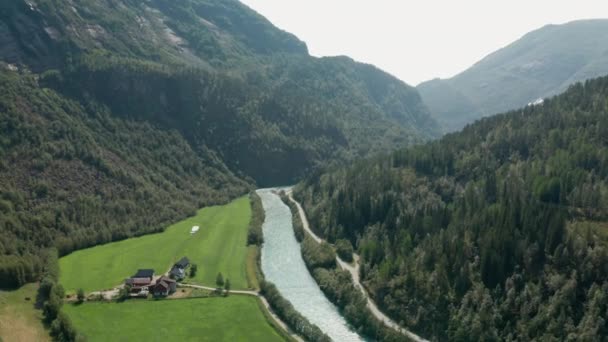 Drone sur la rivière qui coule par la forêt et les bâtiments — Video