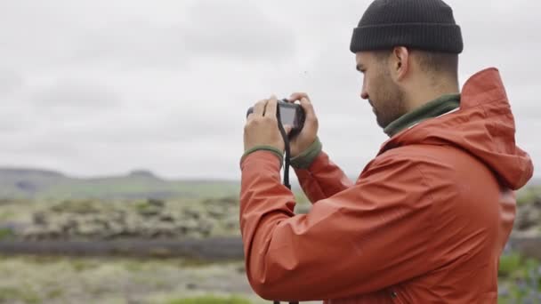 Muž fotografování s fotoaparátem v mechem pokryté krajině — Stock video