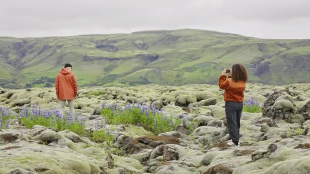 Mulher fotografando homem em paisagem musgosa — Vídeo de Stock