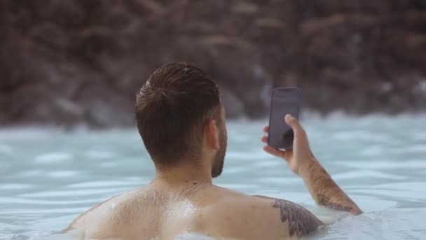 Man använder smartphone på partner i Lagoon Geotermisk Spa — Stockvideo