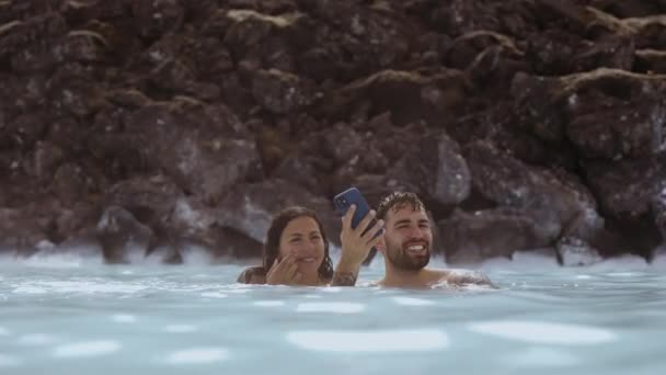 Par tittar på telefon i Lagoon Geotermisk Spa — Stockvideo