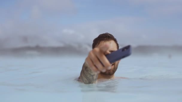 Hombre sonriente con Smartphone en Lagoon Geothermal Spa — Vídeos de Stock