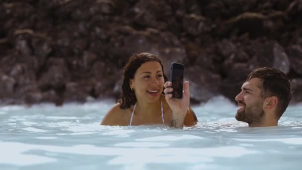 Man Fotografering Flickvän I Lagunen Geotermisk Spa Med Smartphone — Stockvideo