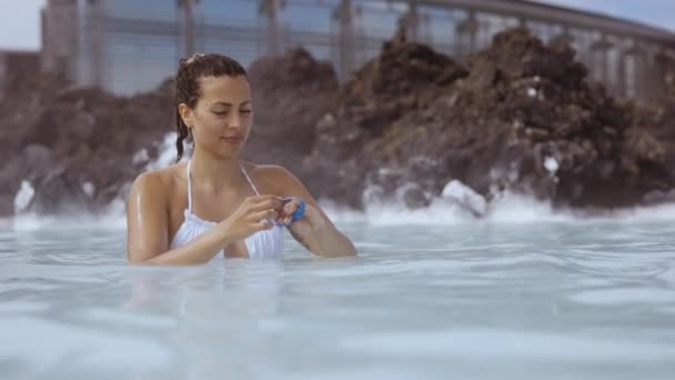 Mulher colocando em alça de pulso na lagoa Geothermal Spa — Vídeo de Stock