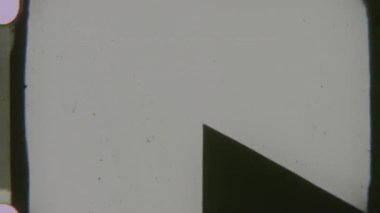 Klasik 8mm film makarası gerisayımı. Siyah ve beyaz bir liderin koyu arkaplanda koyu beyaz bir işaret, film tahılları ve küçük kusurlarla güçlendirilmiş.