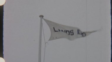 Üzerinde LANDS yazılı beyaz bir bayrak rüzgarda dalgalanıyor, temiz bir gökyüzüne karşı 8 mm 'lik bir filmde yakalandı..