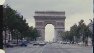 Otomobiller ve motosikletler, Paris 'teki ikonik Zafer Takı' na doğru geniş bir cadde boyunca ilerliyor..